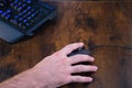 Online video game player`s hand detail. The hand is over the mouse, you can also see the illuminated keyboard on the gaming table Royalty Free Stock Photo