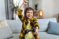 Online win. Happy little boy gamer with joystick celebrating victory in video game, laughing and gesturing to camera Royalty Free Stock Photo