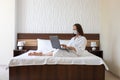 Online working woman at home or hotel room. Laptop and girl in a protective face medical mask. Pandemic in the world