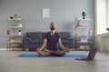 Online yoga class. Peaceful young guy doing morning meditation practice in front of laptop at home. Life balance concept