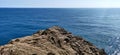 Onlooking blue ocean from a rocky dusty cliff in daylight