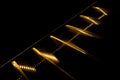 Part of diagonal illuminated by golden stairs on black background.