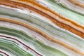 Onyx gemstone texture close up. Green, white, brown and orange stripes. Natural stone mineral background Royalty Free Stock Photo
