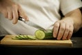 ÃÂ¡ook cuts a cucumber on a wooden board. Royalty Free Stock Photo