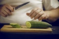 ÃÂ¡ook cuts a cucumber on a wooden board. Royalty Free Stock Photo