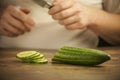 ÃÂ¡ook cuts a cucumber on a wooden board. Royalty Free Stock Photo