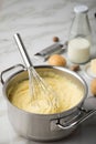 Ooking pot with mashed potatoes and ingredients as potato, milk, salt, butter, nutmeg with whisker and grinder on light marble