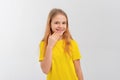 Portrait of embarrassed teen girl use hand cover mouth, stands in casual yellow t shirt over white studio background