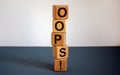 Oops sign on wooden cubes. Beautiful blue table, white background, copy space. Concept