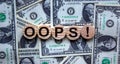 Oops sign on wooden cut circles. Beautiful background from dollar bills. Concept Royalty Free Stock Photo