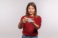 Oops, sorry! Frustrated woman in shaggy sweater looking at smartphone with excuse grimace, feeling helpless