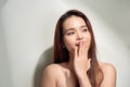 Oops! Surprised young Asian woman covering mouth with hands and staring