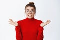 Oops what to I do now. Nervous young woman in glasses worried as making mistake, shrugging and looking aside indecisive Royalty Free Stock Photo