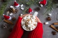 Hot chocolate cup and marshmallows in female hand wearing red sweater, against grey background & Christmas theme Royalty Free Stock Photo