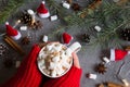 Hot chocolate cup and marshmallows in female hand wearing red sweater, against grey background & Christmas theme Royalty Free Stock Photo