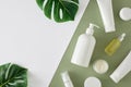 Op view photo of white cosmetic bottle, cream jars, dropper bottles, tropical leaves Royalty Free Stock Photo