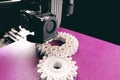 opblique view on process of 3D-printing. print head, bright pink print bed and white helical gears with visible infill and layer