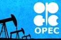 OPEC logo and silhouette industrial oil pump jack on rustic blue background Royalty Free Stock Photo