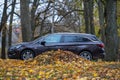Opel Astra ST on the road with autumn leaves in the city park. Autumn landscape