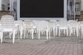 Open air cinema with group of white plastic chairs and black screen in summer day without people Royalty Free Stock Photo