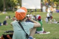 Open air cinema in the park. People sit in groups in isolation from each other. In the foreground, the boy sits