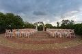 Open air decorated area for the wedding ceremony with a wooden arch decorated with flowers. White wooden chairs decorated with ora Royalty Free Stock Photo