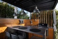 Open-air mini kitchen with wooden parts, trees and sky background