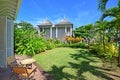 Room view of an open air porch with slightly extended roof and tall full length wooden door overlooking beautiful green garden