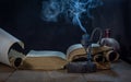 An open ancient book, an extinguished smoking candle in a dark candlestick, and unfolded and rolled scrolls Royalty Free Stock Photo