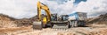 In an open area, under a partly cloudy sky, a dump truck, a loader and an excavator work on a construction site or a sand quarry Royalty Free Stock Photo