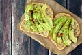 Open avocado sandwiches on paper against rustic wood