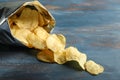 Open bag with crispy potato chips on color wooden table Royalty Free Stock Photo