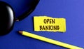 OPEN BANKING text on yellow torn paper on blue background Royalty Free Stock Photo