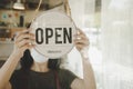 Open. barista, waitress woman wearing protection face mask turning open sign board on glass door in modern cafe coffee shop