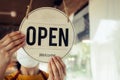 Open. barista, waitress woman wearing protection face mask turning open sign board on glass door in modern cafe coffee shop, cafe Royalty Free Stock Photo