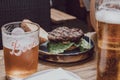 Open beef burger on a plate among beer glasses, selective focus
