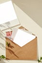 Open beige craft paper envelope with photography mockup under shadows. Collection of greeting cards, postcard