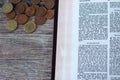 Open bible book prophet Malachi 3 verses for Christian tithing and offering to God Jesus Christ and coin money on wooden table