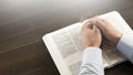 Open Bible book on the table. Prayer. White cup. Young man in shirt prays with folded hands. Royalty Free Stock Photo