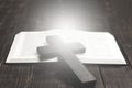 Open Bible book on a wooden table. Wooden cross of Jesus. Light from a book. The concept of love for God`s Word. Royalty Free Stock Photo