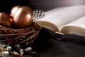 Open Bible on a dark table, eggs in a nest  and feather on dark background.  Easter greeting card Royalty Free Stock Photo