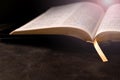 Open Bible on a dark table with light coming from above. Christianity concept. Holy Bible background Royalty Free Stock Photo