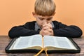 An open Bible in front of a praying child with folded hands Royalty Free Stock Photo