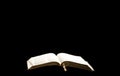 The open Bible lies on an isolated black background. The concept of a relationship with God