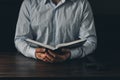 Open Bible. A man in a shirt is holding a book. Cross crucifixion. The concept of God's love. On a wooden background. Royalty Free Stock Photo