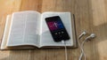 open bible with phone and headphones,Concept listen the words of God.Bible, phone and earphones on wood table, top view Royalty Free Stock Photo