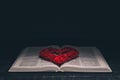 Open Bible. Red heart on the book. Holy Bible. On a black background. Royalty Free Stock Photo