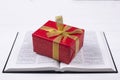 An open Bible on the table. A gift on a book. A red gift-wrapped box with a gold bow. A gift from God Royalty Free Stock Photo