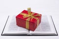 An open Bible on the table. A gift on a book. A red gift-wrapped box with a gold bow. A gift from God Royalty Free Stock Photo