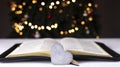 An open Bible on the table. The heart is a symbol of God\'s love for people. Prayer. On the background of the Christmas tree Royalty Free Stock Photo